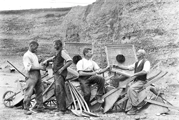 Gruppe von Männern bei einer Arbeitspause mit Schoppen im Kieswerk